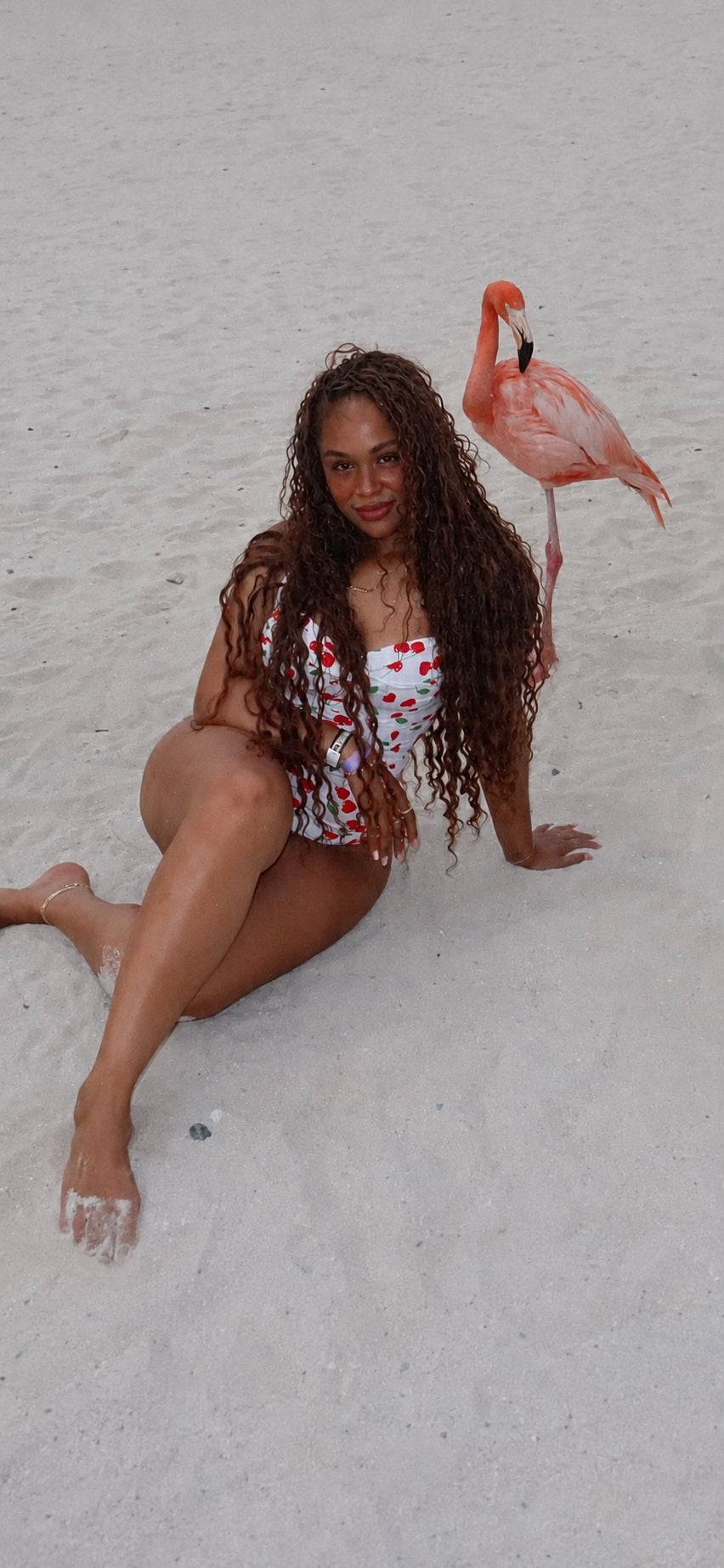 Client wearing long HBTBEAUTY curls beside a flamingo