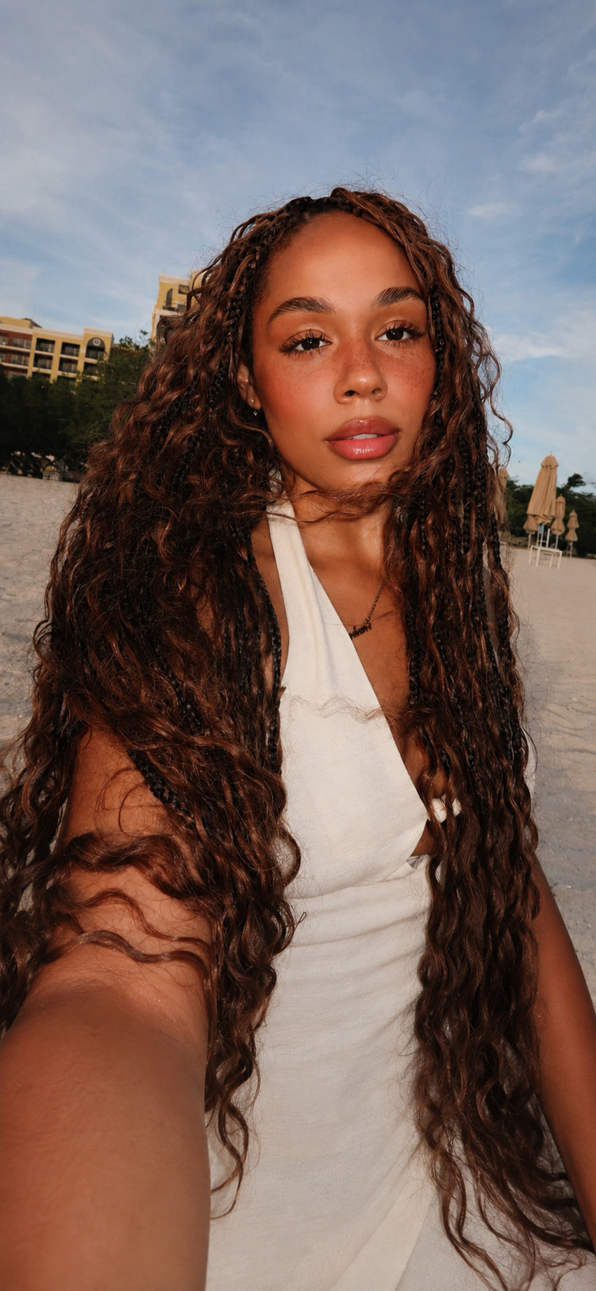 Client wearing long warm-brown HBTBEAUTY boho curls on the beach